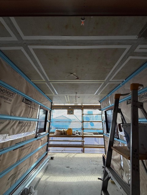 Commercial fit-out interior with insulation wrap and a taped-out concrete ceiling.